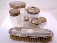 A small collection of silver topped dressing table jars and a silver backed dressing table brush.