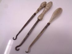 Three silver handled button hooks.