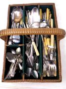 A vintage wicker cutlery basket containing a quantity of silver plated cutlery