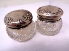 A pair of glass dressing table pots with silver pots.