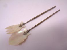 Two pieces of silver plated cutlery with mother of pearl fish decoration.