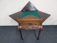 A 20th century heavily carved Chinese style envelope card table fitted with four drawers