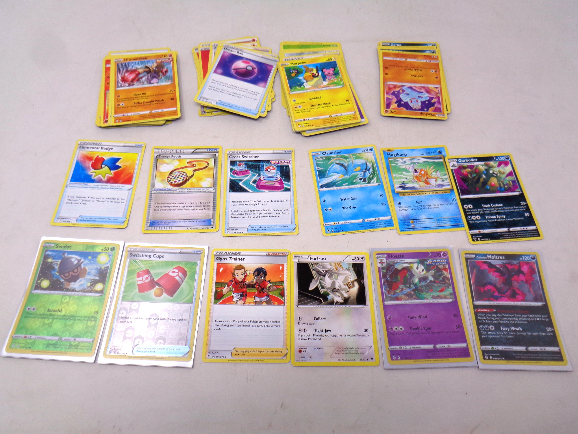 A collection of Pokemon cards, foil, energy and trainer cards.