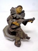 A vintage metal car mascot modelled as a dancing figure playing a lute