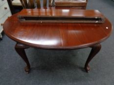 An Edwardian oval mahogany wind out dining table with two leaves