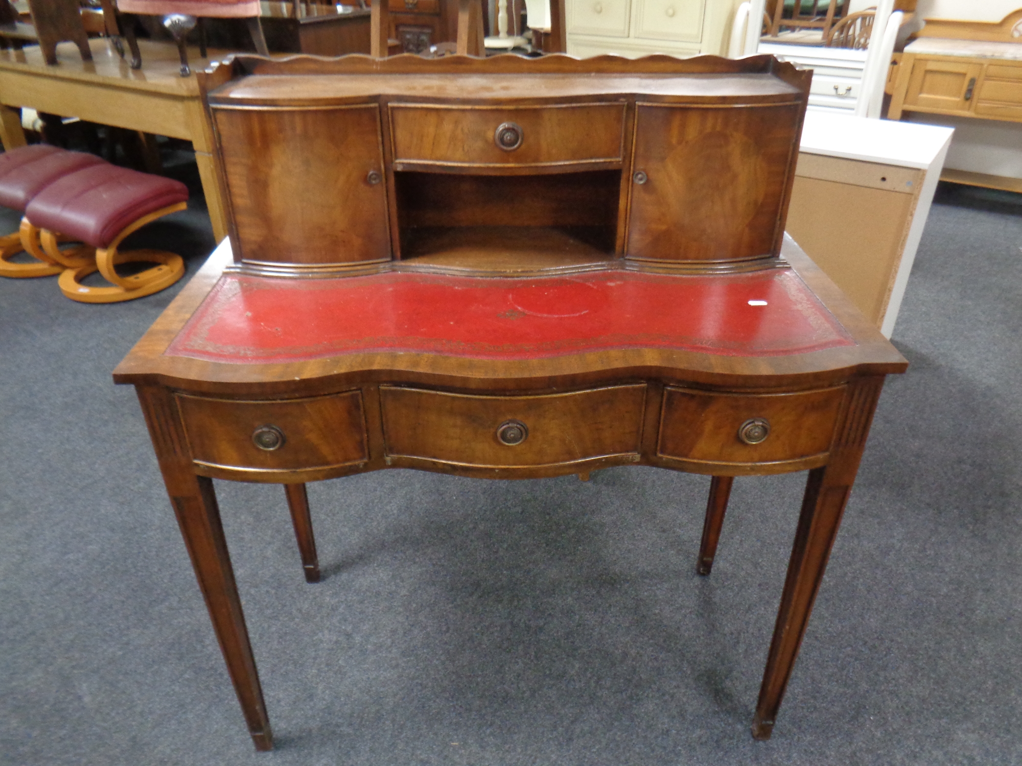 A mahogany serpentine fronted writing table on raised legs