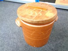 A glazed stoneware twin handled crock pot with wooden lid