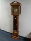 A contemporary oak cased granddaughter clock with pendulum and key