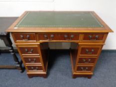 A Yew wood twin pedestal writing desk fitted nine drawers with a tooled green leather inset