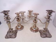 A pair of silver plated candlesticks together with two three-way silver plated candelabra.
