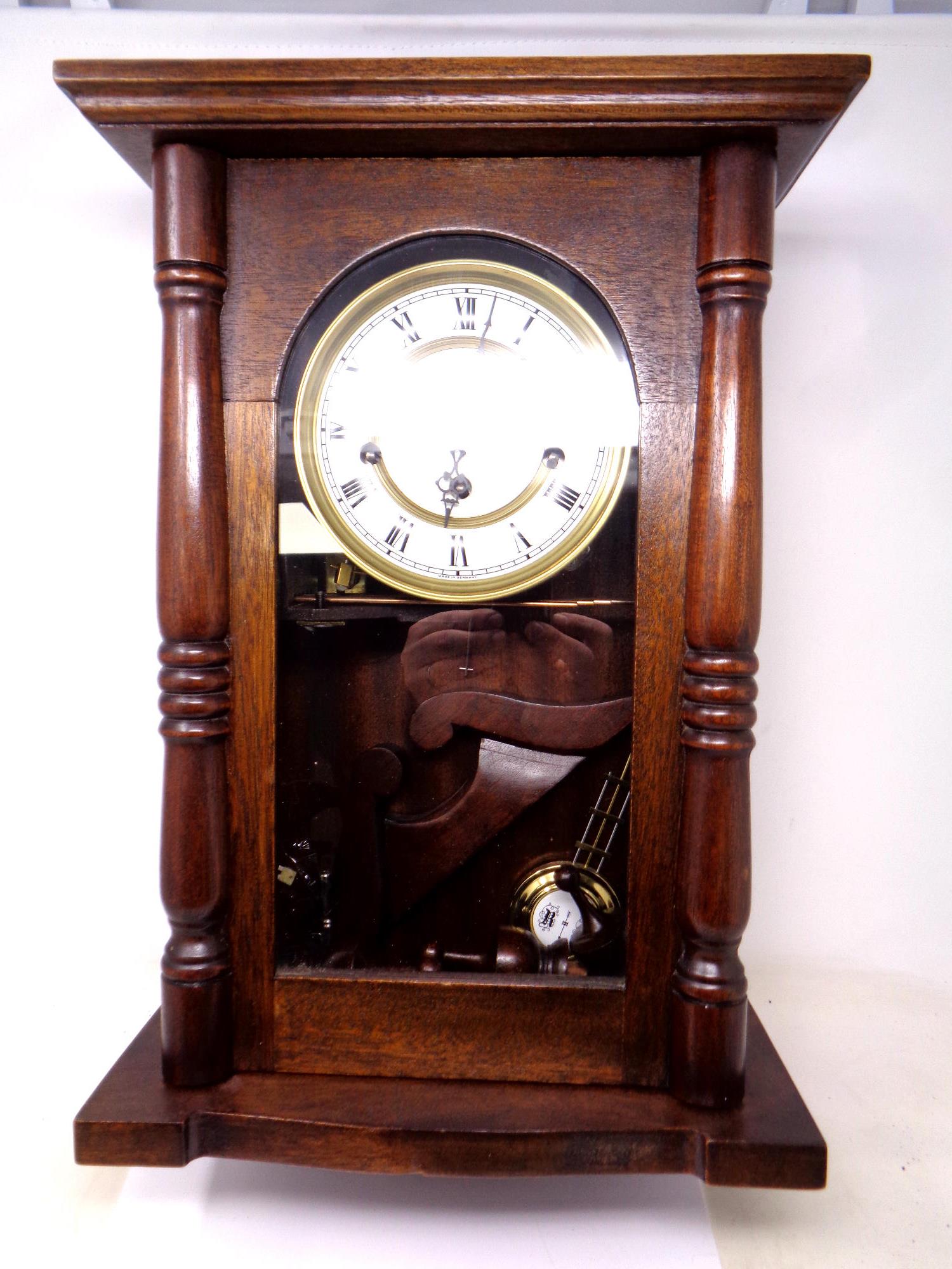 A contemporary German wall clock with pendulum and key.