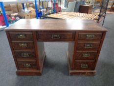 An Edwardian oak twin pedestal desk fitted nine drawers