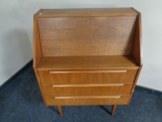 A mid 20th century teak writing bureau fitted drawers on raised legs