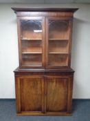 A Victorian mahogany glazed double door bookcase fitted double door cupboard beneath (associated)