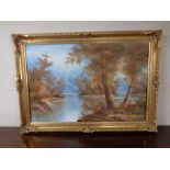 A decorative gilt framed oil on canvas, river through a wooded landscape.