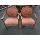 A pair of Edwardian beech salon armchairs upholstered in a pink brocade fabric