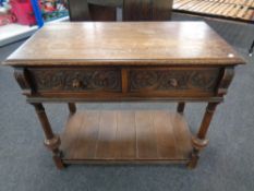 An Edwardian carved oak two tier side table fitted two drawers