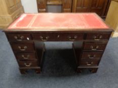 A mahogany twin pedestal writing desk fitted nine drawers with a red tooled leather inset panel