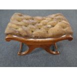 A brown buttoned leather upholstered footstool on X-frame support