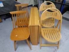 A narrow pine drop leaf kitchen table together with a pair of folding chairs and a further pair of