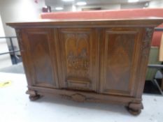 An early 20th century triple door sideboard with carved central panel door on bun feet