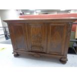 An early 20th century triple door sideboard with carved central panel door on bun feet