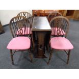 An oak drop leaf dining table together with a set of four wheel back chairs