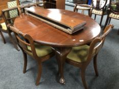 An Edwardian oval mahogany wind out dining table with two leaves