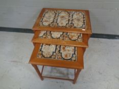 A mid 20th century nest of three teak tile topped tables.