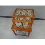 A mid 20th century nest of three teak tile topped tables.