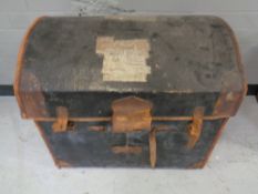 An antique leather bound dome topped trunk bearing railway luggage labels.