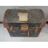 An antique leather bound dome topped trunk bearing railway luggage labels.