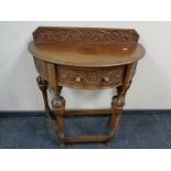 An early 20th century carved oak D-shaped hall table fitted a drawer