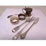 A silver mustard pot, two napkin rings and four pieces of cutlery.