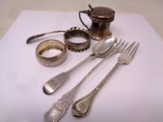 A silver mustard pot, two napkin rings and four pieces of cutlery.