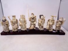 A set of seven Japanese carved bone figures on wooden stand