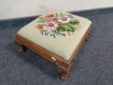 An embroidered footstool on carved lion paw feet