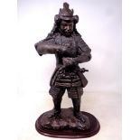 A metal patinated figure of a samurai on wooden base (lacks sword)