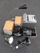 A box containing a Panasonic video camera, headphones, two angle poised lamps.