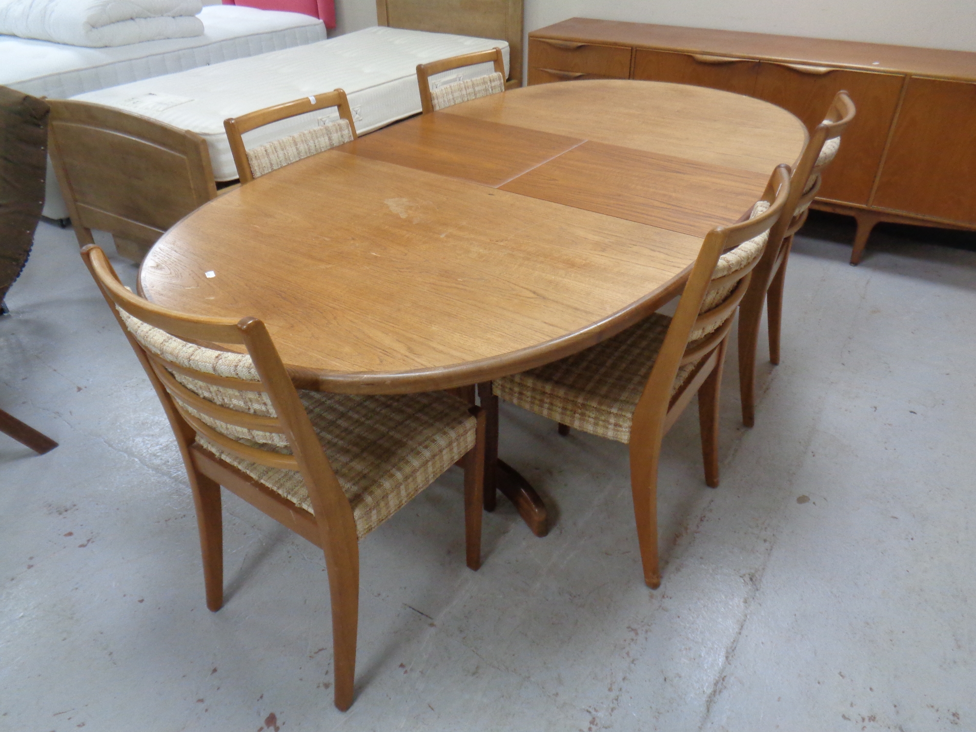 A mid 20th century teak oval G plan extending dining table fitted a leaf together with a set of