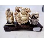 Three carved Japanese ivory and pen work netsuke on wooden stand together with a carved bone sword