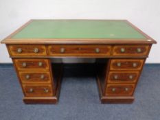 A mahogany and satinwood inlaid twin pedestal writing desk fitted nine drawers with green tooled
