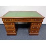 A mahogany and satinwood inlaid twin pedestal writing desk fitted nine drawers with green tooled