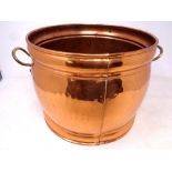 A circular copper and brass handled coal bucket
