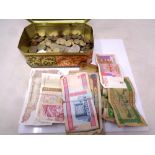 A tin containing a quantity of foreign currency, both coins and notes, from The Gambia, Jordan,