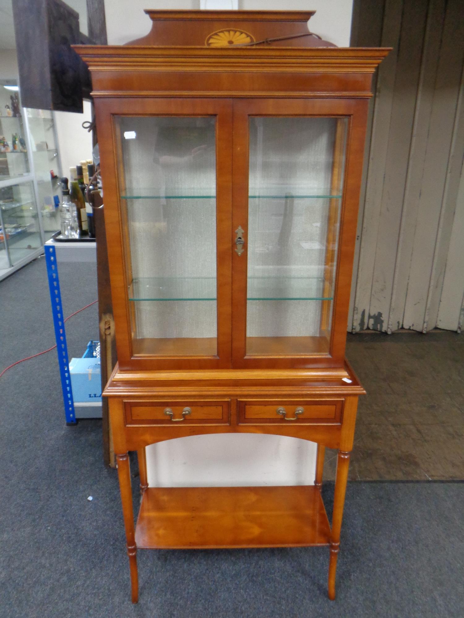 A Bradley yew wood double door display cabinet on stand,