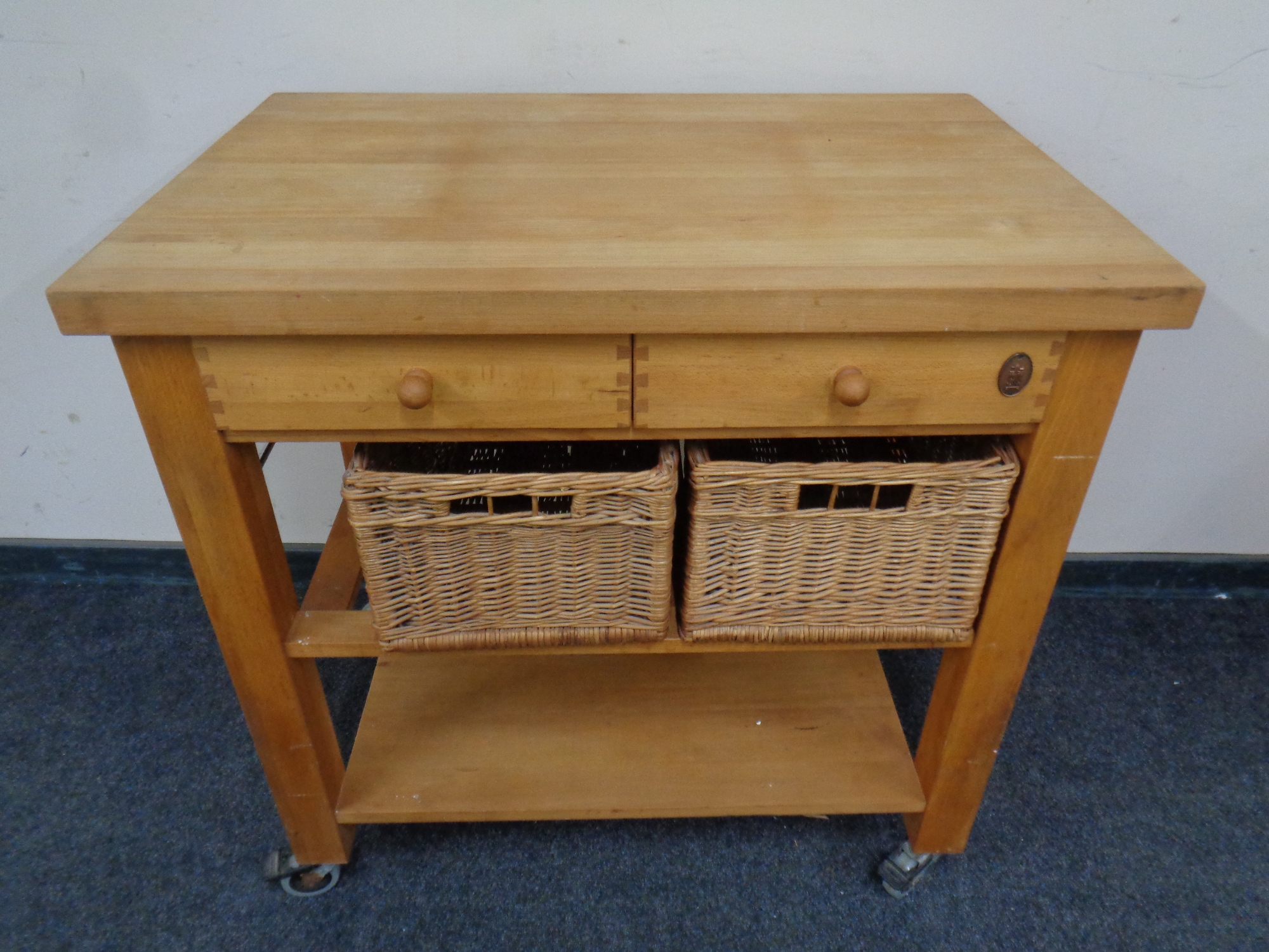 A pine kitchen island with drawers and storage baskets beneath