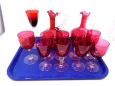 A tray containing two antique cranberry glass jugs together with ten further cranberry glass and