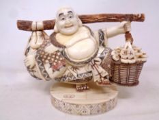 A Japanese carved bone and penwork figure of a man carrying baskets