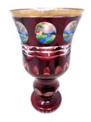 A ruby glass goblet with eight hand painted panels and gilt rim, height 18.5 cm.